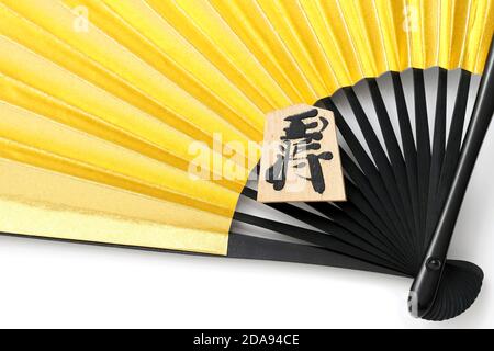 Japanische Shogi Stücke und Sensu auf weißem Hintergrund, Shogi ist japanisches Schach. Das Wort, das in dem Stück geschrieben ist, ist König. Stockfoto