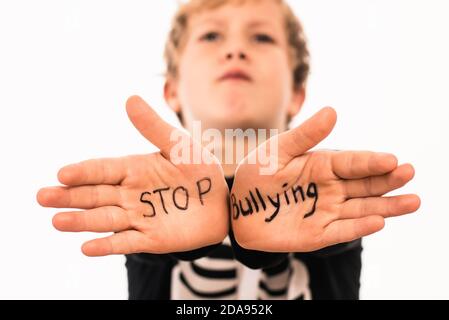 Scared Boy zeigt seine Hände mit dem Slogan Stop Mobbing, isoliert auf weiß. Stockfoto