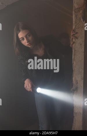 Neugieriges junges Mädchen erkunden dunklen, gruseligen Keller mit einer Fackel Stockfoto