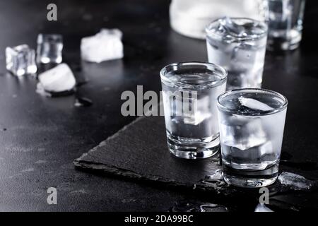 Gefrorener Vodka in Schnapsgläsern auf schwarzem Hintergrund, eisgekühltes starkes Getränk Stockfoto