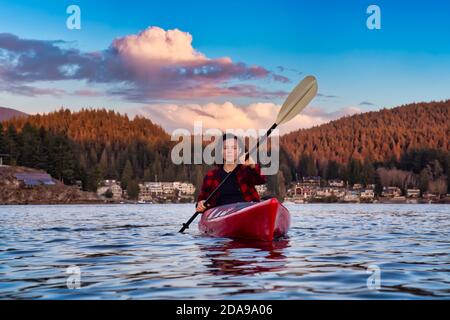 Abenteuerliches Mädchen paddelt auf einem hellen roten Kajak Stockfoto