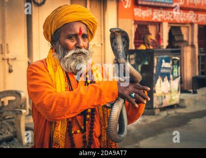 heilige baba Mönch heilige hypnotisieren eine Schlange Cobra Kundalini mit Flöte auf der Straße von varanasi, Indien. Stockfoto