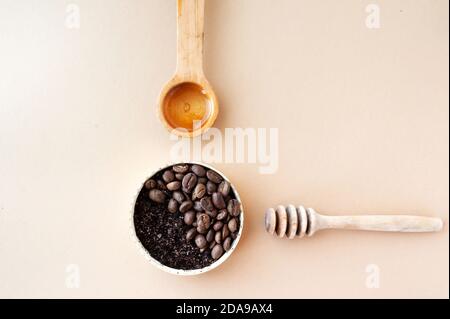 Kaffee Peeling und Kaffeebohnen in Gold-Glas, Holz Honigstock und kosmetisches Öl ordentlich auf pastellbeige Hintergrund organisiert, Home Kosmetik, Kosmetik l Stockfoto