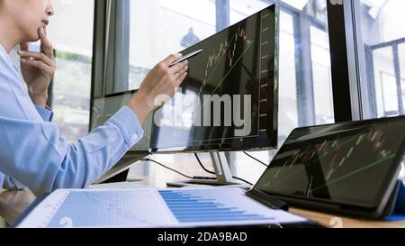 Börsenhändler arbeiten mit Graphen, Diagramme auf Monitor in modernen Handelsbüro. Stockfoto