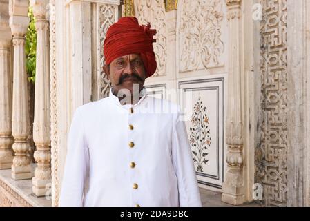 Indische Mann trägt traditionelle Kleidung roten Turban am Eingang des City Palace, Rajasthan, Nordindien. Stockfoto