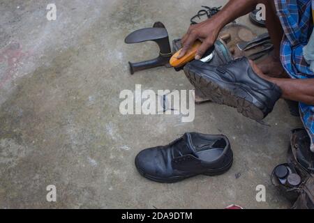 Indische lokale Schuster Reparatur Schuhe neben der Straße von Hand mit Werkzeugen in traditioneller Weise. Natürliche Schuss Darstellung der täglichen Arbeit eines regelmäßigen Schuster. Stockfoto