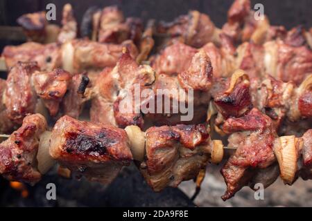 Geröstete Fleischstücke zum Rauchen im Grill, Braten Grill mit Freunden oder Familie im Urlaub. Das Schweinefleisch wird auf Feuer gebraten. Stockfoto