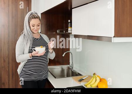 Glücklich attraktive junge schwangere Frau essen gesundes Frühstück in ihr Küche Stockfoto