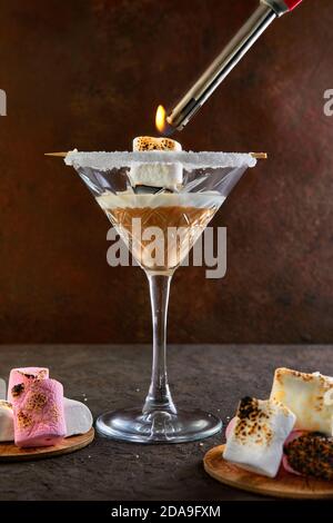 Irischer Cremelikör in einem martini-Glas mit Marshmallows Lichter mit einem Feuerzeug. Stockfoto