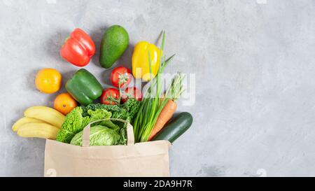 Papier-Shopping-Box voll mit frischem Bio-Gemüse und Obst auf grauen Tisch Draufsicht. Eco-Shopping oder Food Delivery Konzept. Stockfoto