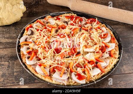 Vorbereitung hausgemachte ungekochte Käse Pizza mit Nudelholz und Teig. Pizza vorbereitet, um in den Ofen gestellt werden Stockfoto