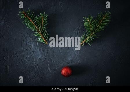 Weihnachtshirsch aus Tannenzweigen und festlicher Kugel auf dunklem Grund. Weihnachtskonzept Stockfoto