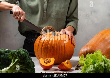 Frau schneidet großen Kürbis in der Küche. Nahaufnahme. Stockfoto