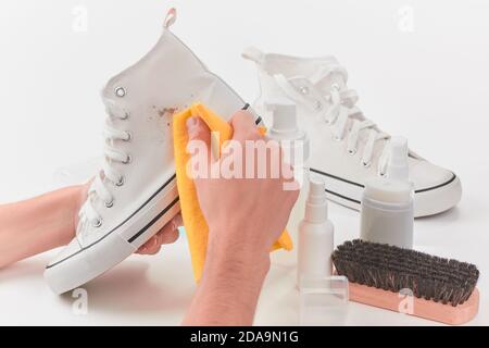 Mann, der einen Fleck Schmutz von einer weißen Leinwand entfernt Sneaker Stockfoto