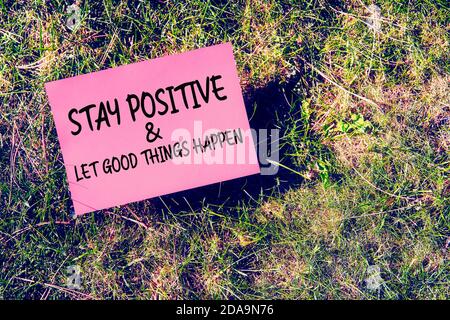 Bleiben Sie positiv und lassen Sie gute Dinge passieren Nachricht auf Papier auf Gras Hintergrund geschrieben. Inspirierendes Zitat für Motivation, Glück oder Erfolg in rel Stockfoto