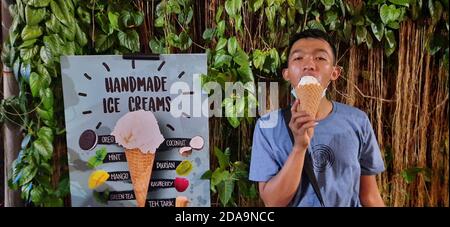 Junger asiatischer Mann genießt es, handgemachte Eiscreme zu essen Stockfoto
