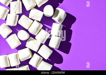 Marshmallows auf violettem Hintergrund mit Kopierbereich. Flach liegend. Draufsicht. Hintergrund oder Textur von bunten Mini Marshmallows. Winter Food Hintergrund Stockfoto