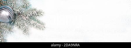 Fichtenzweig mit Weihnachtsspielzeug und Perlen auf schneebedecktem weißem Hintergrund. Eine Weihnachtskarte, Postkarte. Stockfoto