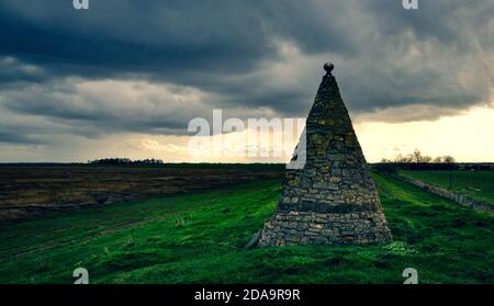 Steinmonument in Freiston Shore, Boston, Lincolnshire, um an die Menschen zu erinnern, die die Verteidigung des Meeres in der Gegend unter einem düsteren Himmel errichteten. Stockfoto