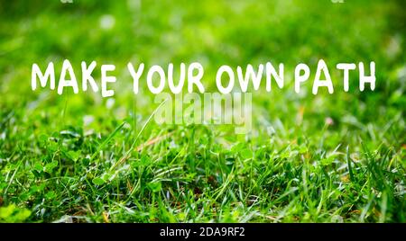Motivationszitat Machen Sie Ihren eigenen Weg auf grünem Gras Garten Hintergrund. Individualität, Führung und das Finden eines einzigartigen Konzepts. Stockfoto