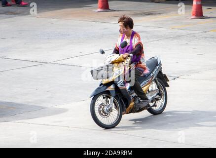 SAMUT PRAKAN, THAILAND, JUNI 30 2020, EINE Frau im Schürze mit Gesichtsmaske fährt ein Motorrad Stockfoto