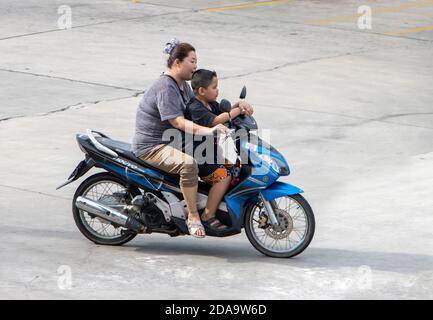 SAMUT PRAKAN, THAILAND, JUNI 30 2020, Frau fährt ein Motorrad mit einem kleinen Jungen zwischen einem Lenker Stockfoto