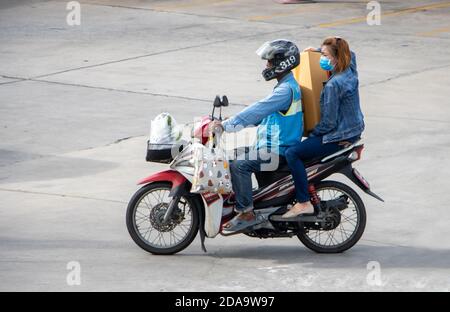 SAMUT PRAKAN, THAILAND, JUNI 30 2020, EIN Taxifahrer auf einem Motorrad fährt mit einer Frau und ihrem Kauf. Stockfoto