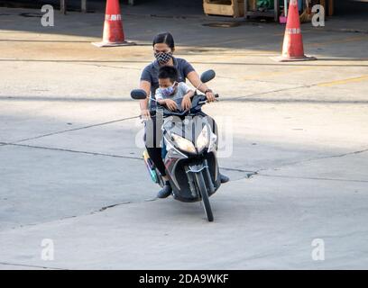 SAMUT PRAKAN, THAILAND, JUNI 30 2020, Frau fährt ein Motorrad mit einem kleinen Jungen zwischen einem Lenker Stockfoto