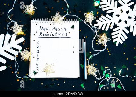 Neujahrsziele. Die Liste der Vorsätze in einem Notizblock auf dunkelgrünem Hintergrund. Resolution Aspirations Motivationskonzept Stockfoto