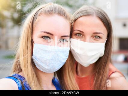 Millennial Frau Freunde nehmen Selfie lächelnd hinter Gesichtsmasken - Neue normale Sommer Freundschaft Konzept mit jungen Mädchen Spaß haben Gemeinsam Stockfoto