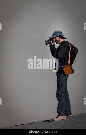 Ein Fotograf hält seine Kamera, um Fotos zu machen, vor dem Hintergrund des Sandes Nubra Valley in Ladakh. Stockfoto