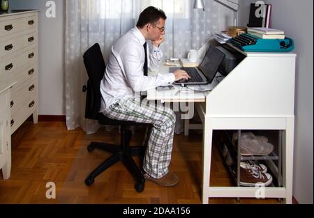 Mann Telearbeit mit Hemd, Krawatte und Pajama-Hose Stockfoto