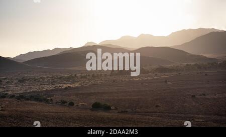 Panoramablick auf die Wüste bei Sonnenuntergang, Bergschichten in einer nebligen Landschaft, Sonne hinter den Hügeln, trockene Landschaft am Mittelmeer. Cabo Stockfoto