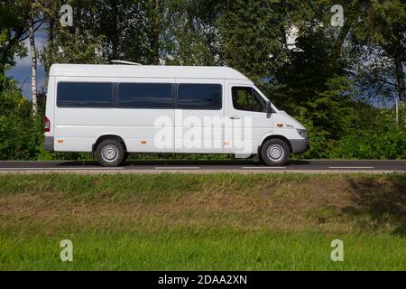 Minibus geht auf der Landstraße entlang des Waldes Stockfoto