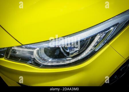 Close-up LED Xenon-Scheinwerfer von gelbem modernen Auto mit Halogenlampen-Technologie für die Beleuchtung Tag und Nacht. Stockfoto