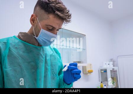 Krankenschwester mit individueller Schutzausrüstung, die das Ergebnis eines Schnelltests auf Covid-19, Coronavirus, Antigene beobachtet. Stockfoto