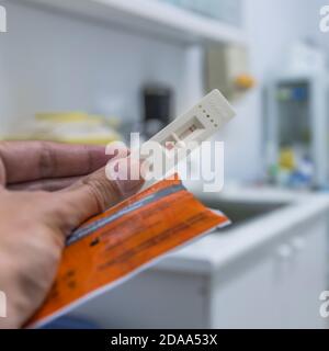 Hand hält einen echten Coronavirus-Schnelltest mit negativem Ergebnis auf einer Krankenhausstation. Covid-19 Stockfoto