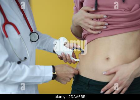 Arzt hält Butyrometer in den Händen und misst Patienten Fettfalte In der Klinik Nahaufnahme Stockfoto