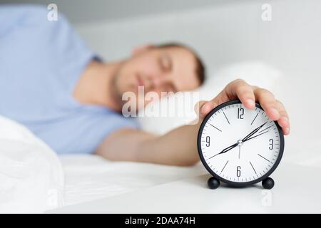 Good Morning Konzept - Nahaufnahme von schläfrigen Mann drehen Wecker am Nachttisch ausgeschaltet Stockfoto