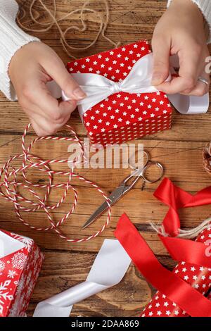 Frau bindet eine Schleife auf einem eingewickelten Geschenk Stockfoto