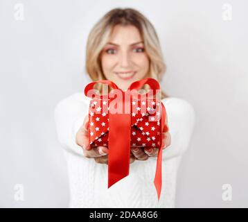 Lächelnde junge Frau hält präsent in den Händen. Selektiver Fokus Stockfoto