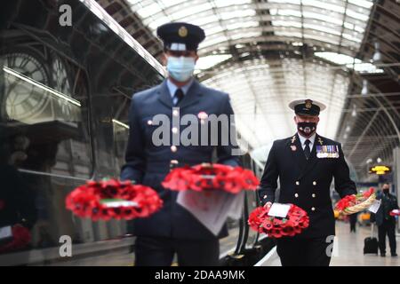 Militärangehörige tragen Mohnkränze am Bahnhof Paddington in London für „Mohnblumen nach Paddington“. Die Great Western Railway (GWR) und die Veterans Charity transportieren Gedenkkränze aus ganz Großbritannien mit dem GWR-Zug nach London Paddington, wo die Kränze um das Kriegsdenkmal des Bahnhofs gelegt werden, um zwei Minuten lang an die Kriegtot am Waffenstillstandstag zu erinnern. Stockfoto