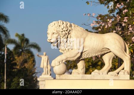 Kuba, Cienfuegos, Parque Martí, Steinlöwe am Eingang des Parks, in der Ferne ist Marmorstatue von Jose Marti - ein kubanischer Revolutionär und Intellektueller Stockfoto