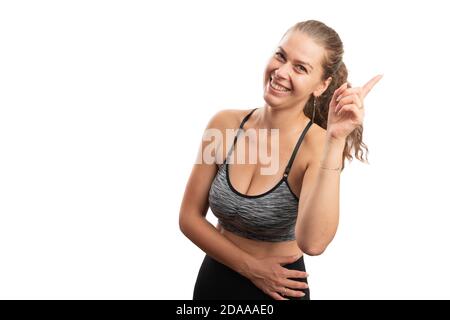 Sportliche Erwachsene Frau lächelt als gute Idee Gedanken Geste Mit Zeigefinger in Sport Fitness-Training Kleidung mit blank Copyspace für sportliche Stockfoto