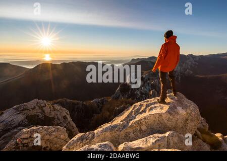 Kletterer steht auf der Bergspitze und wachende Sonnenuntergang Stockfoto