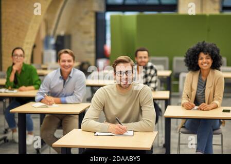 Geschäftsvortrag. Gruppe von glücklichen multirassischen Menschen lächeln an der Kamera während des Seminars, selektive Fokus auf fröhliche kaukasischen Mann. Bildung und Selbstverbesserung Stockfoto