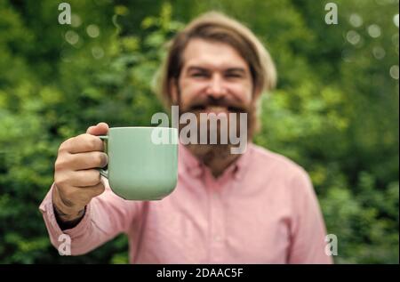 Morgeninspiration. Fühlen Sie echtes Glück. Voller Energie. Heißer Tee in der Tasse. Zeit für das Mittagessen. Kleine Kaffeepause. Bärtige Mann entspannen im Freien. Glücklicher Mann trinken frischen Morgenkaffee. Guten Morgen für Sie. Stockfoto