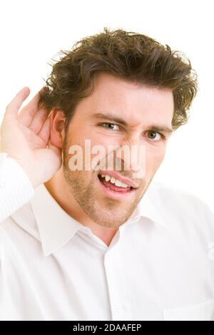 Der junge Mann hört mit der Hand hinter dem Ohr Stockfoto