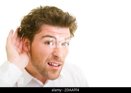Der junge Mann hört mit der Hand hinter dem Ohr Stockfoto