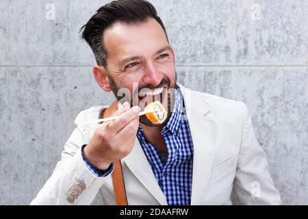 Nahaufnahme Porträt von glücklich reifen Mann essen Sushi mit Essstäbchen Stockfoto